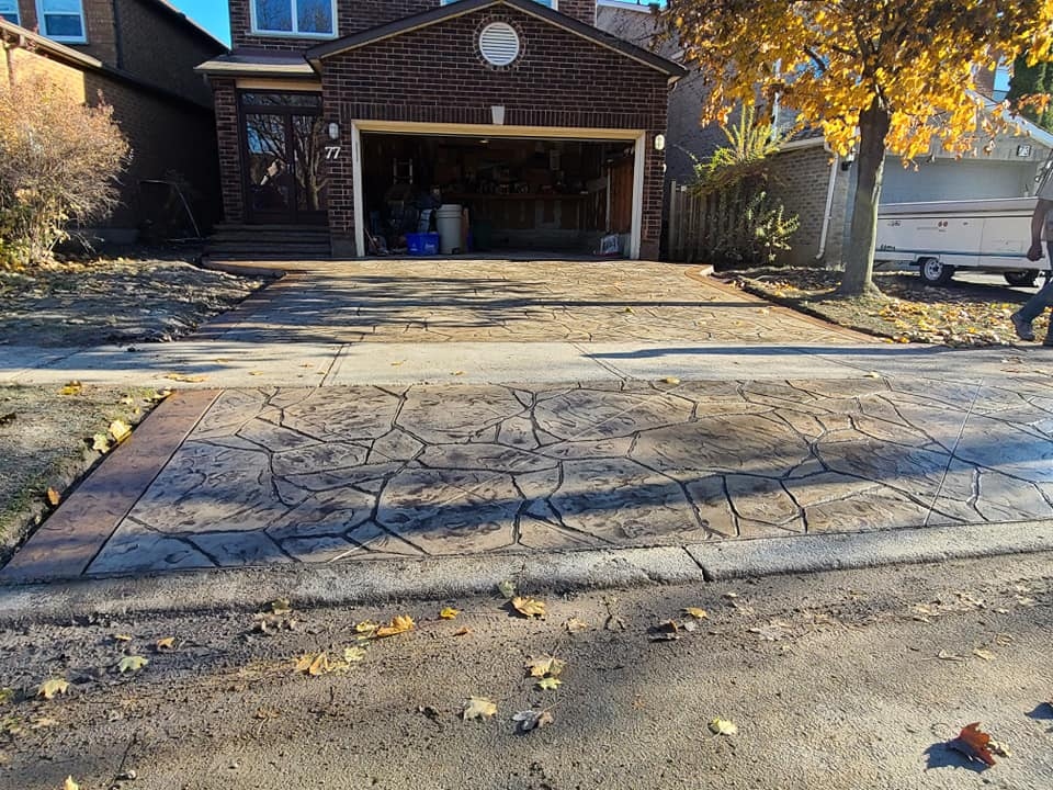 Large flagstone-stamped driveway in charcoal and brown tones, fall setting