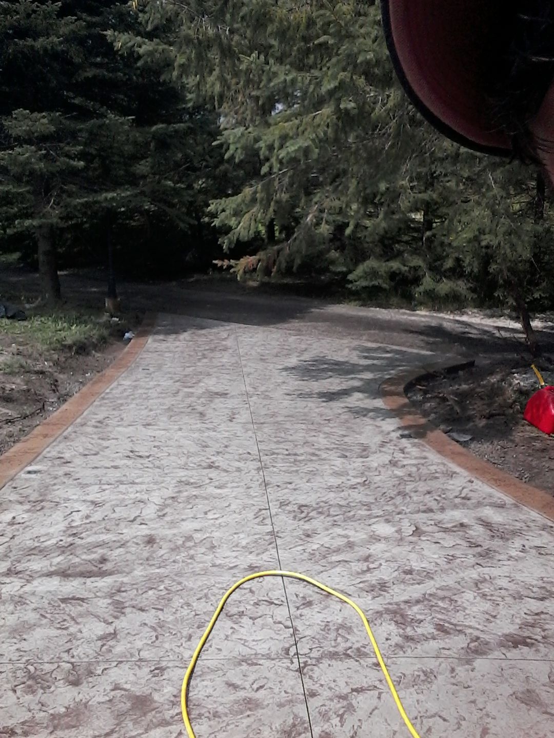 Stamped flagstone laneway with brown border on treed property