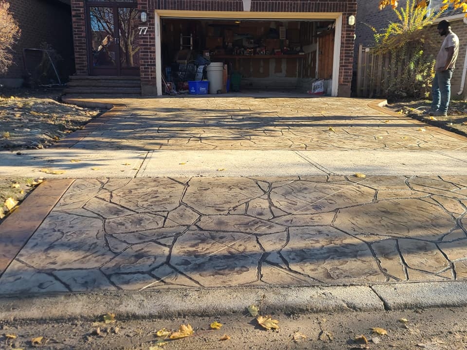 Wide view of flagstone-stamped driveway with crew member