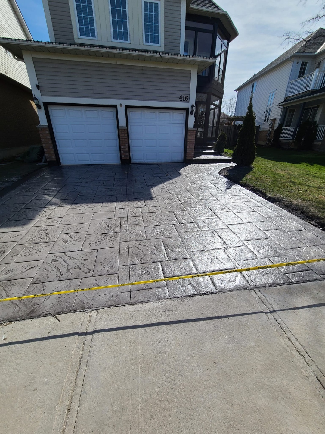 Double-garage stamped marble tile driveway, dark grey with caution tape
