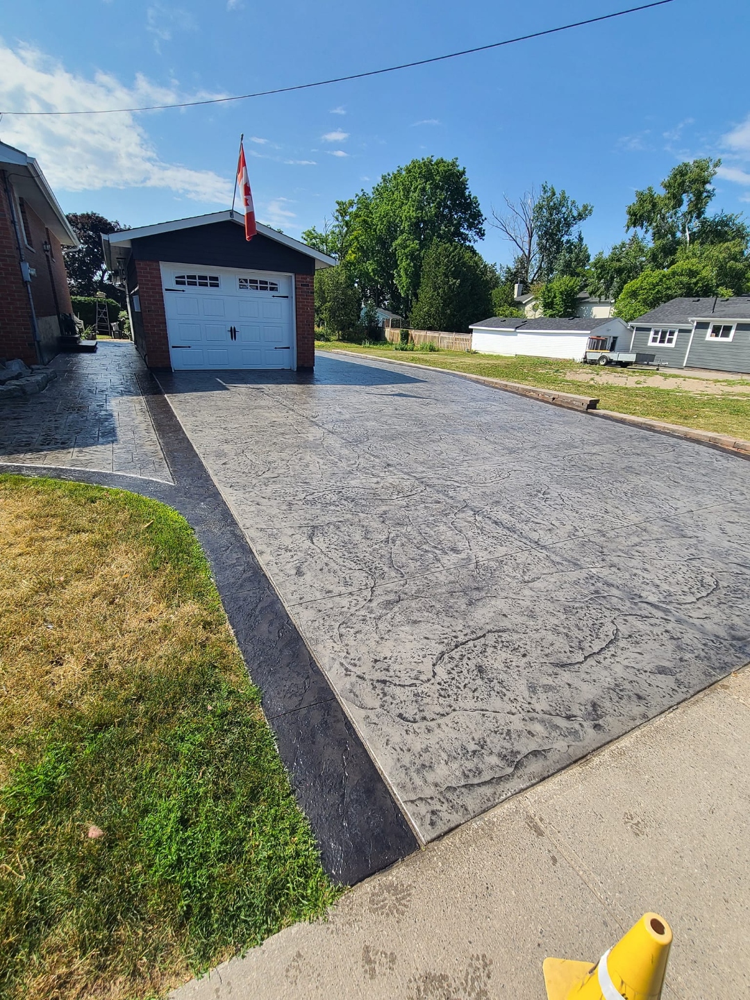 Wide stamped driveway with herringbone border in bright summer sun
