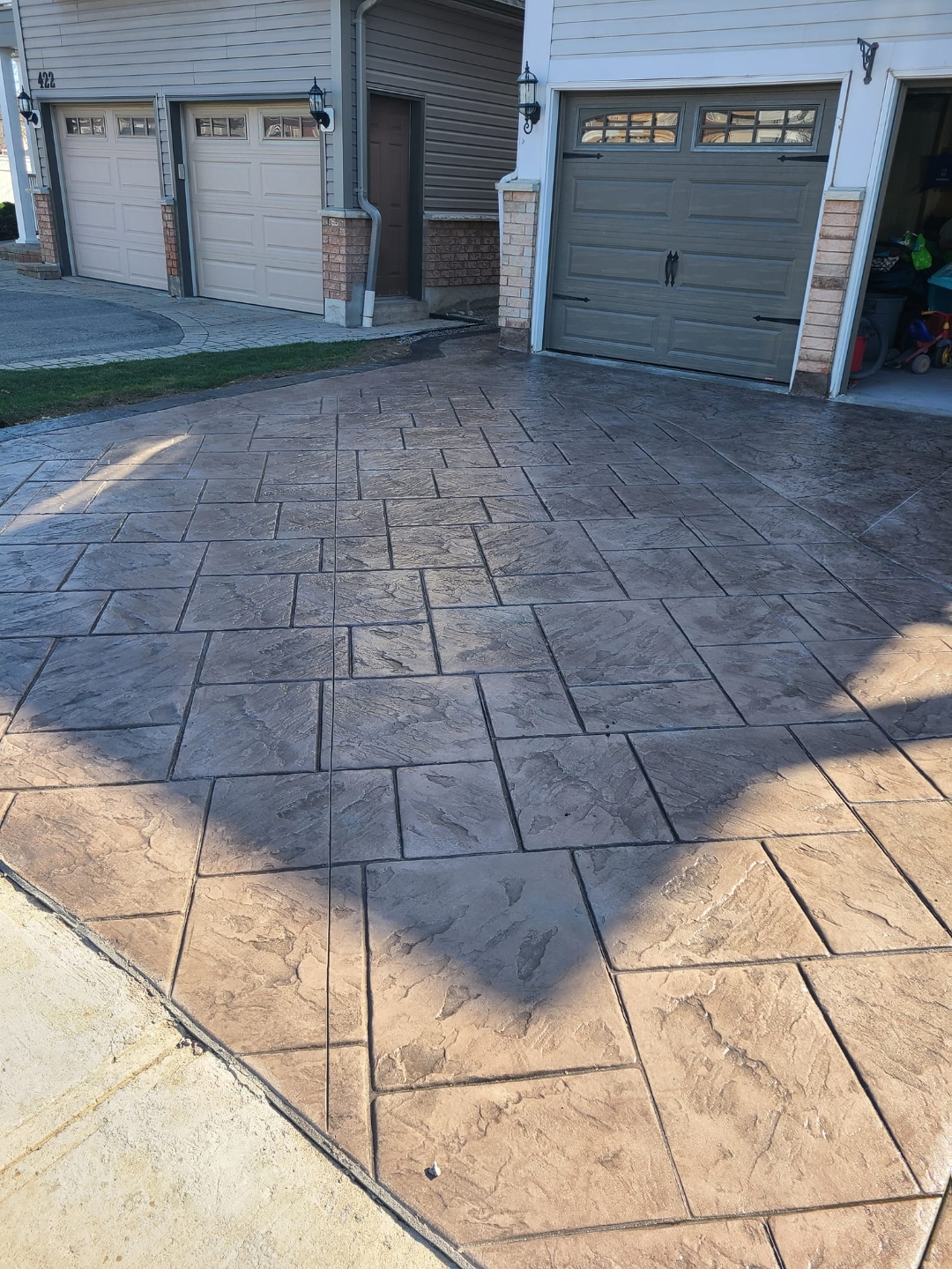 Large brown and charcoal stamped tile driveway serving triple-car garage