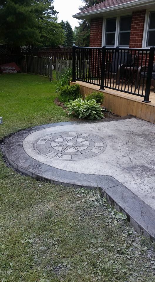 Curved backyard stamped concrete patio with compass rose inlay and garden