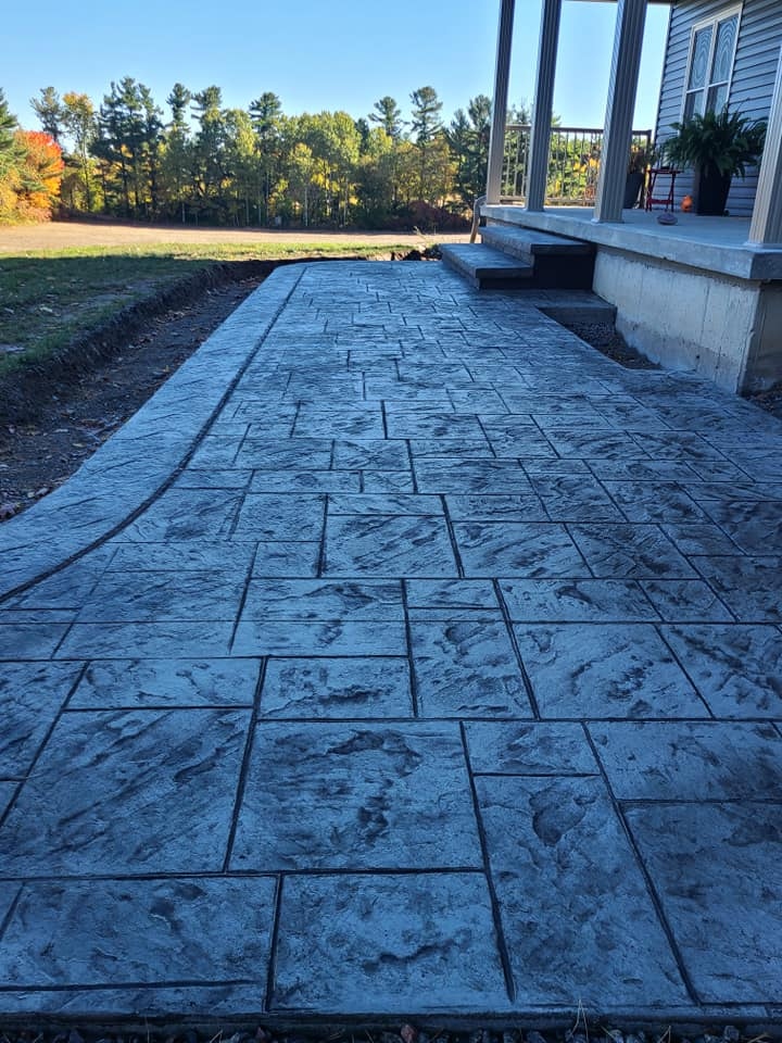 Long grey stamped tile patio beside country home with fall foliage