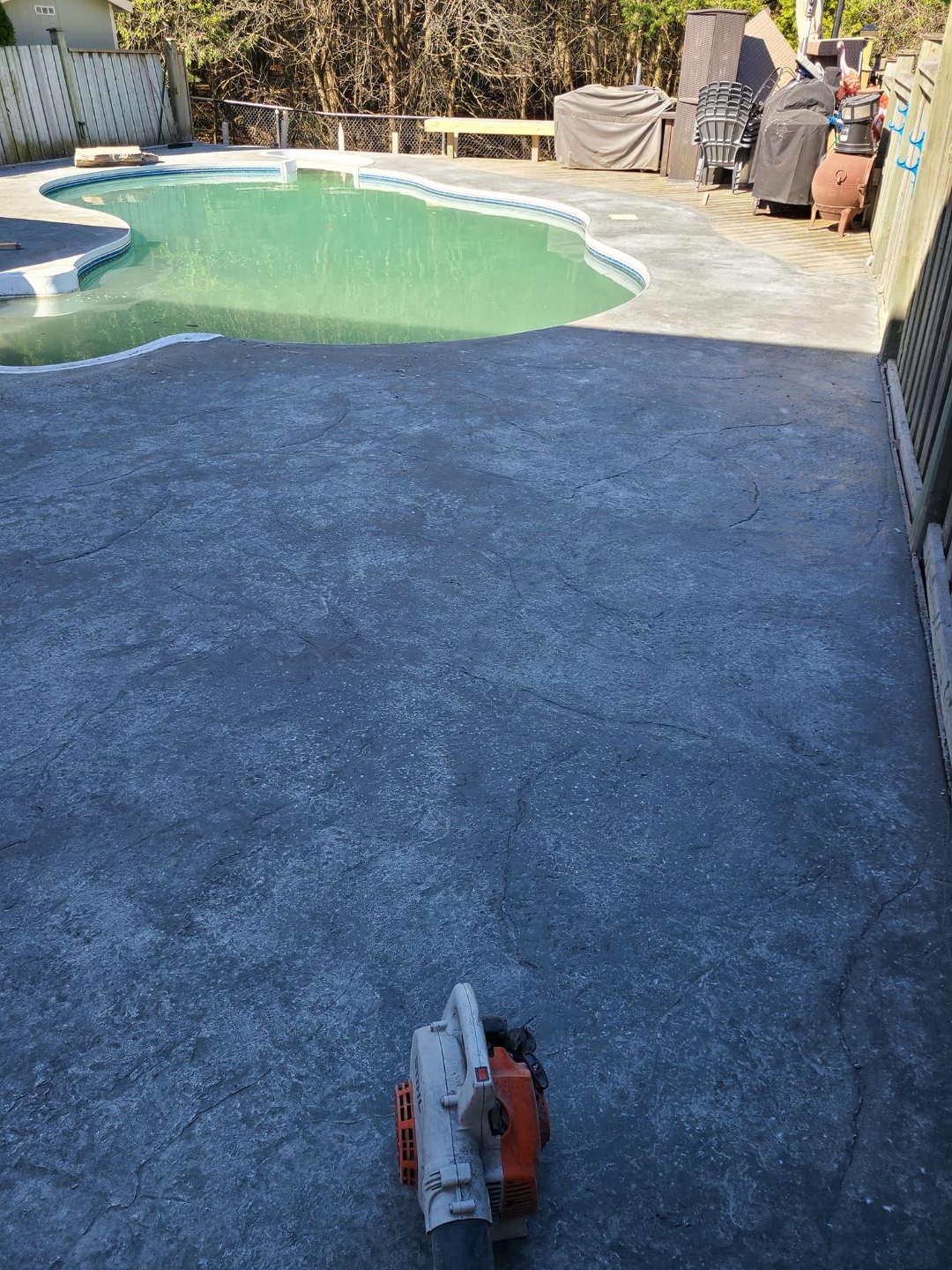 Finished dark flagstone stamped concrete pool deck around kidney pool