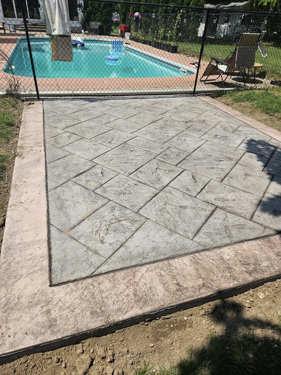 Stamped herringbone concrete pad beside pool