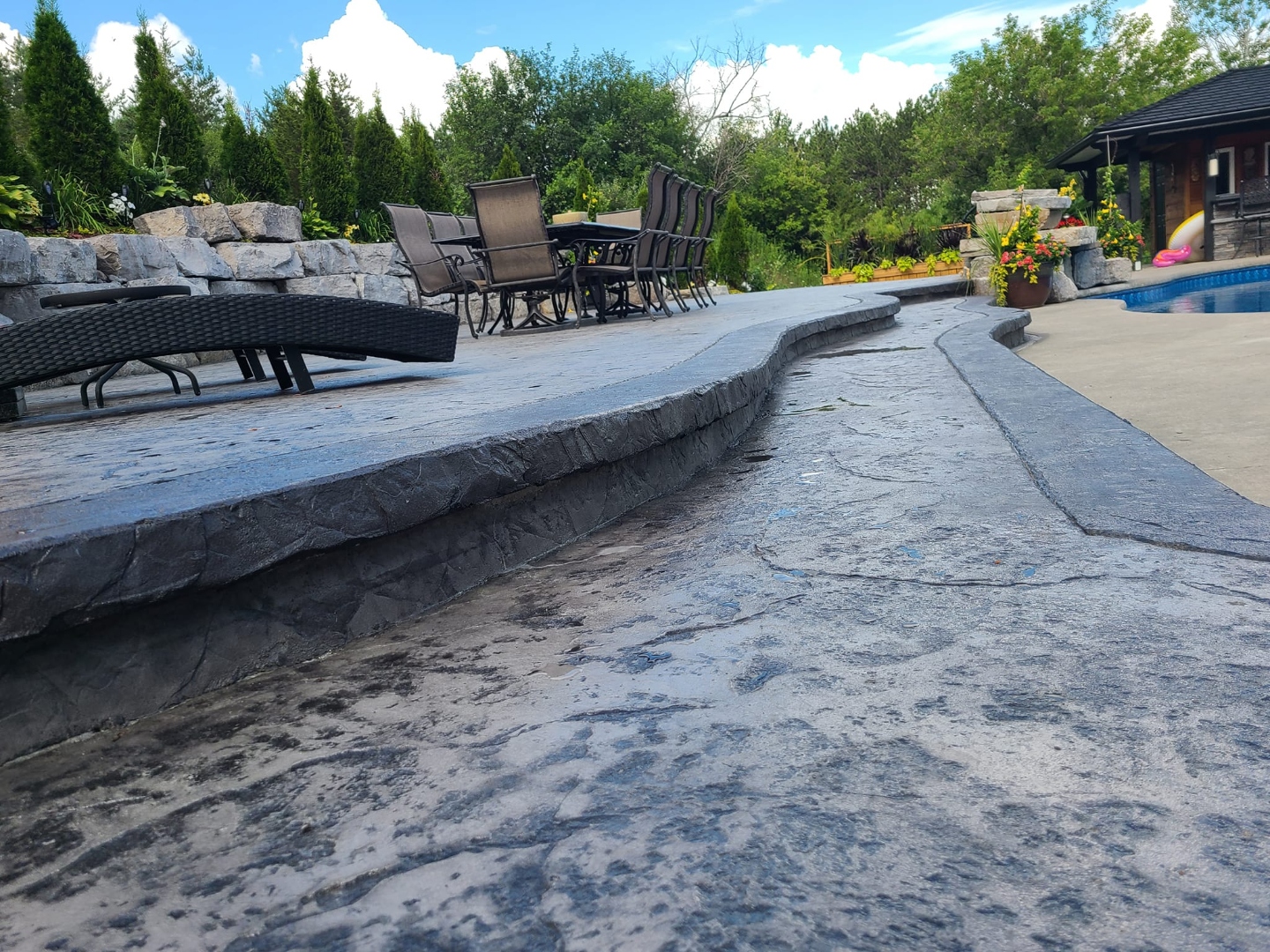 Large stamped patio with raised level, pool, and stone retaining walls