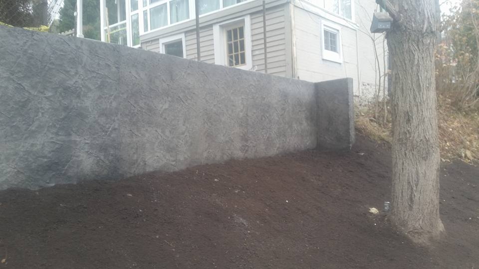 Dark grey textured stamped concrete retaining wall