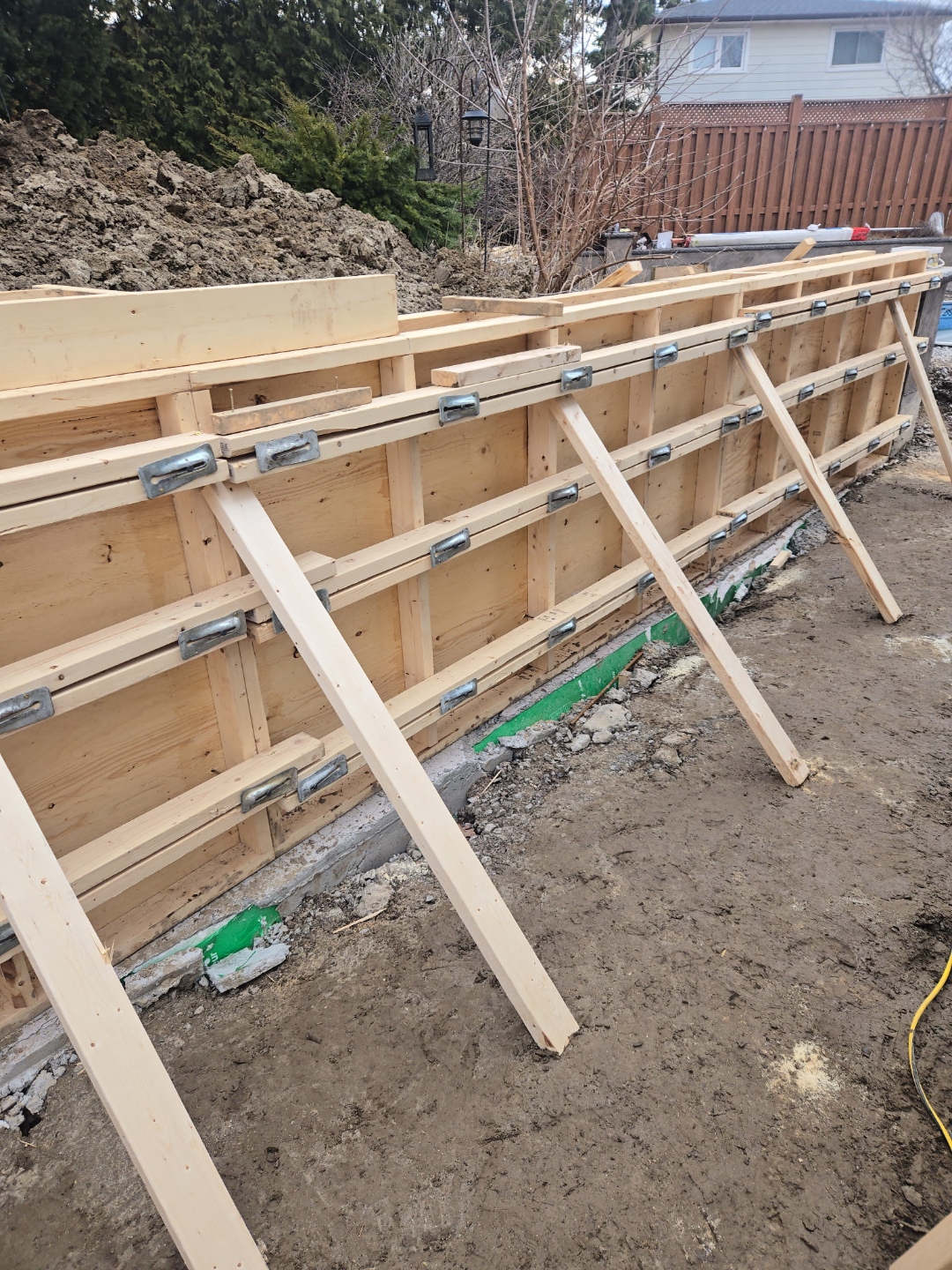 Long retaining wall formwork with bracing, under construction