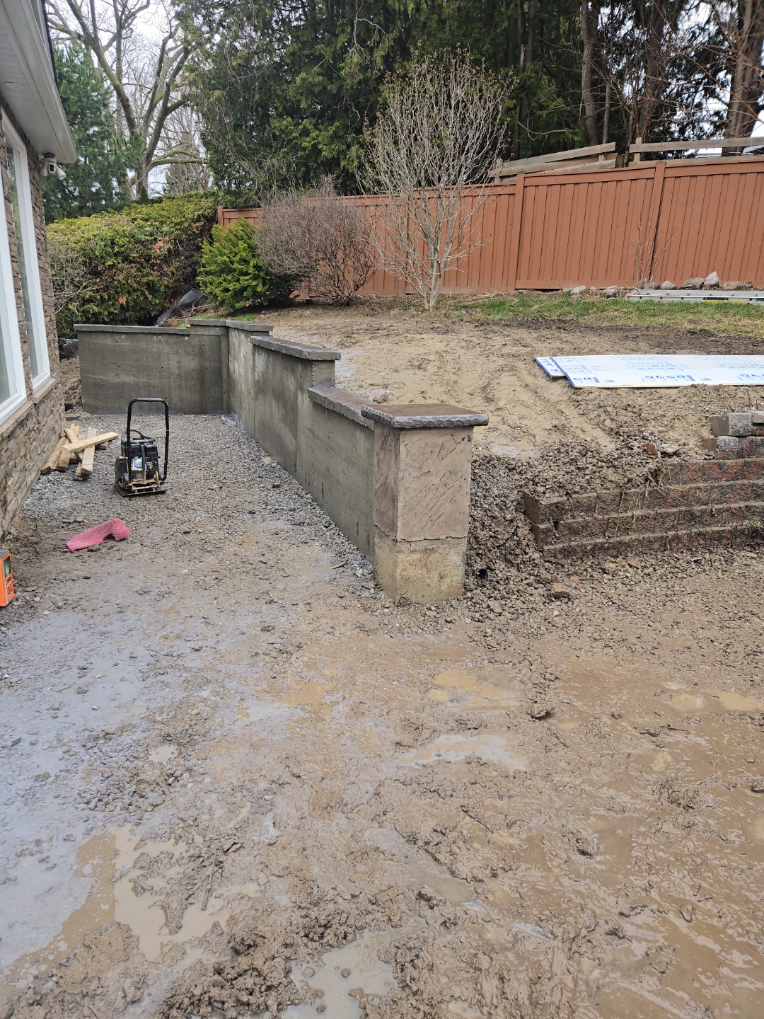 Finished concrete retaining wall with stamped capped pillars, wide view