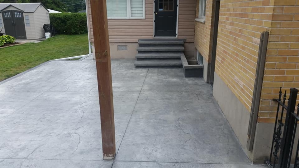 Grey stamped flagstone backyard concrete slab with dark steps