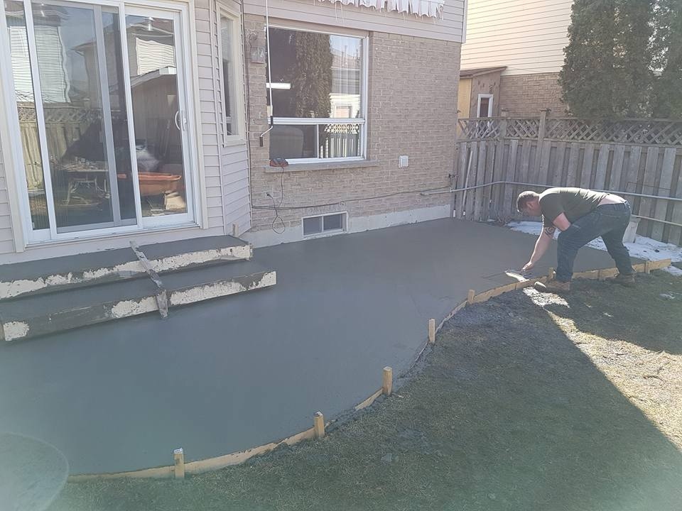 Crew screeding and levelling fresh backyard concrete slab pour