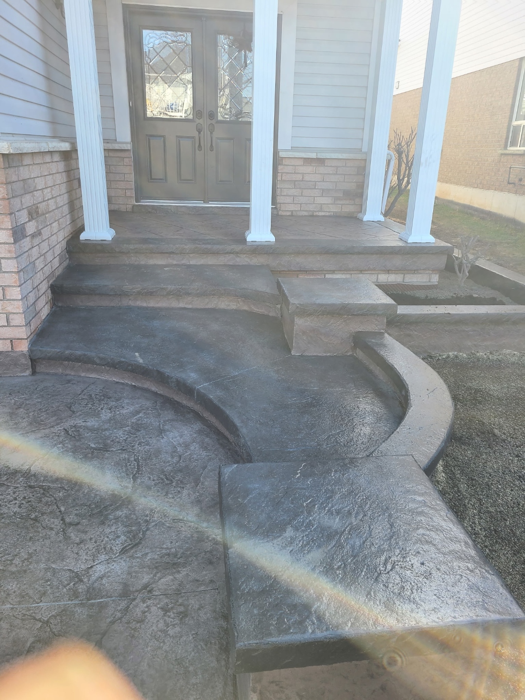 Curved dark stamped concrete stairs with columns