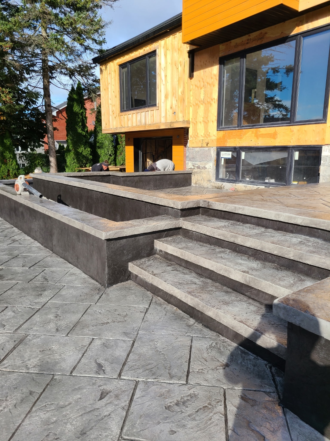 Large dark stamped patio with stairs on modern home under construction