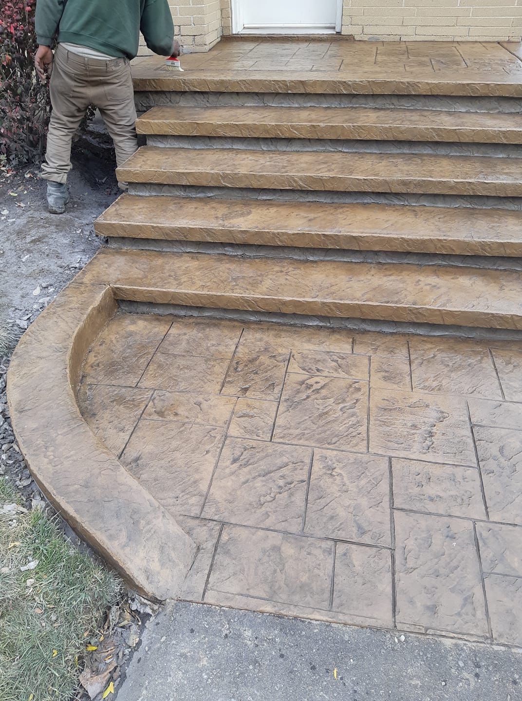 Tan and brown stamped concrete 5-step entry staircase with curved landing