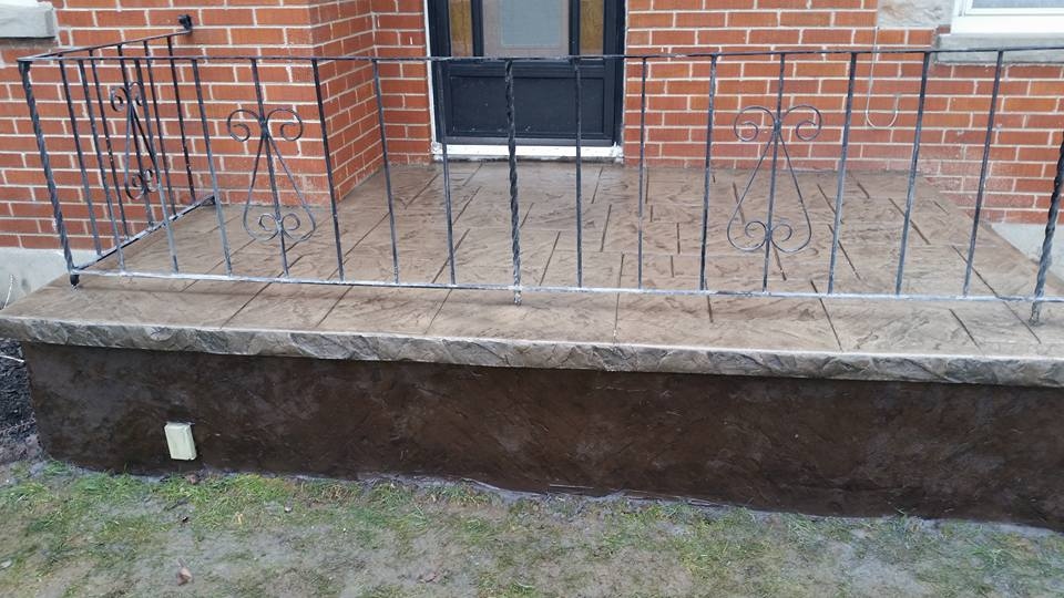 Tan and brown stamped raised front porch with decorative iron railing