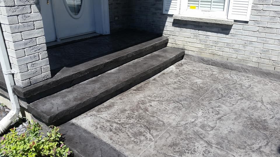 Dark charcoal stamped step and flagstone landing at grey brick home