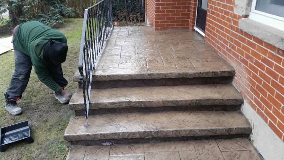 Crew sealing tan stamped concrete steps with ornate iron railing