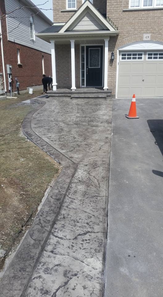 Dark grey stamped flagstone walkway curving to front entrance