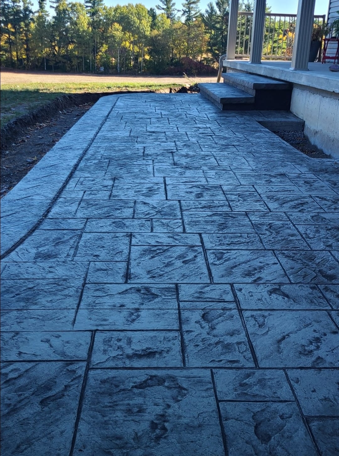 Dark grey herringbone walkway with curved border and fall trees