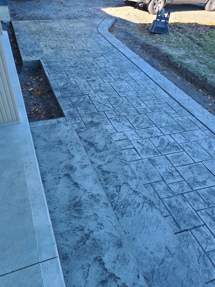 Charcoal stamped tile walkway with curved border and planter bed