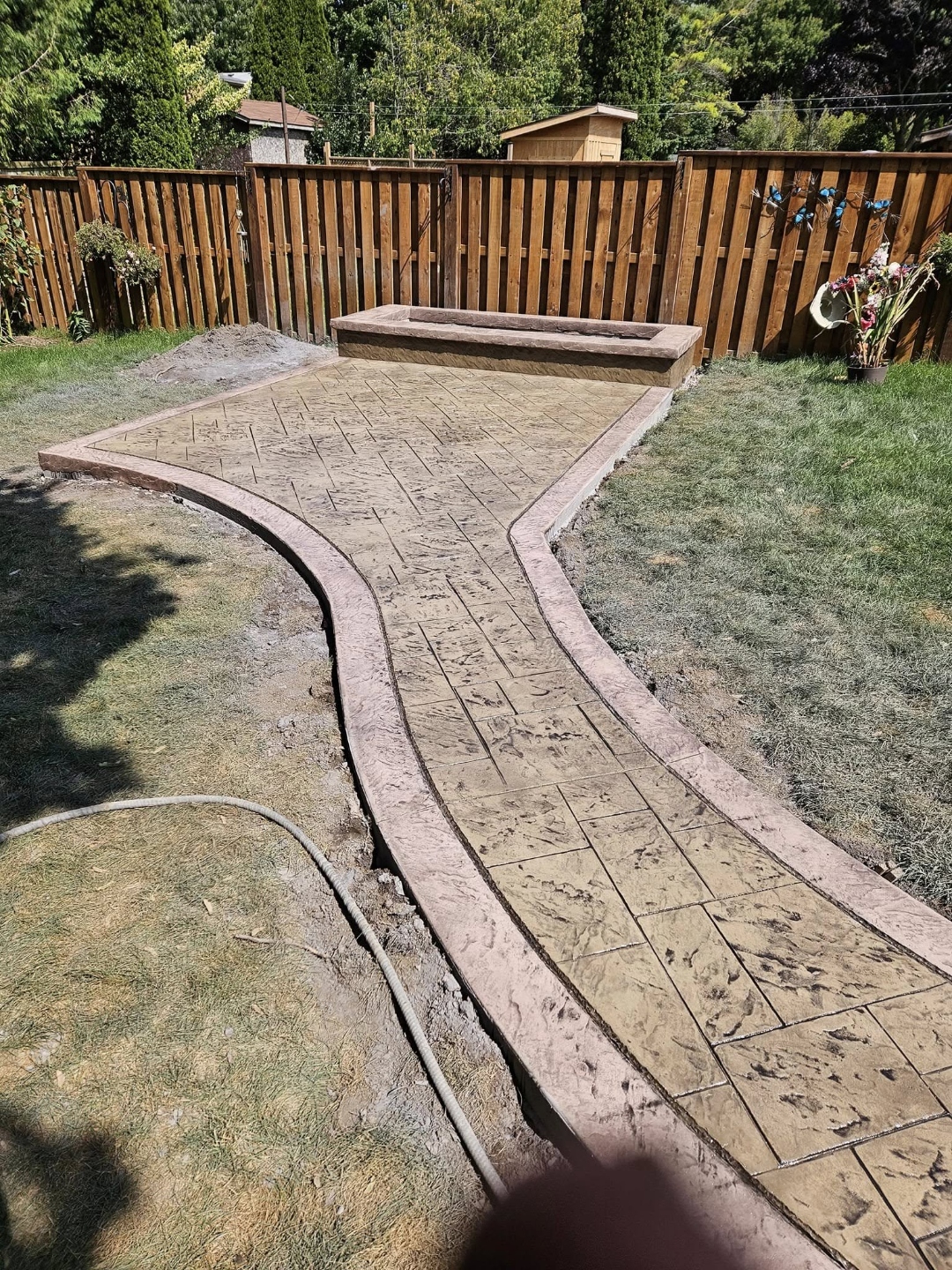 Winding stamped backyard path with built-in planter box